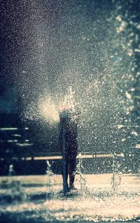 Full length of man standing on wet road during winter at night