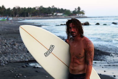 Midsection of shirtless man standing at beach
