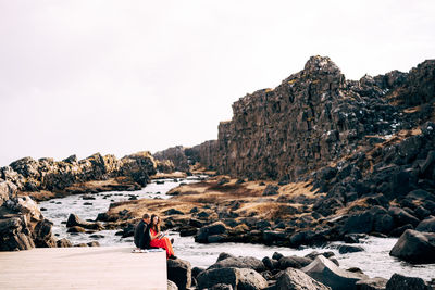 Rear view of people on rock formations against sky