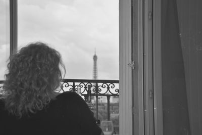 Rear view of woman looking through window