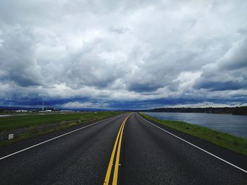 Empty road against cloudy sky at dusk