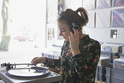 Young woman listening to record in a record store