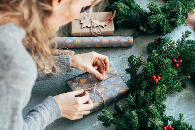 Midsection of woman wrapping christmas presents on table