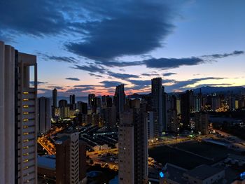 Illuminated buildings against sky at dusk