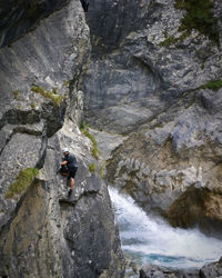 Climber climbing on rock by river