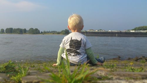 Rear view of boy in lake against sky