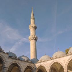 White mosque arcade with minaret against blue summer sky