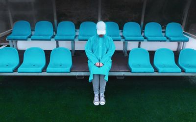 Woman in blue raincoat sitting on chair