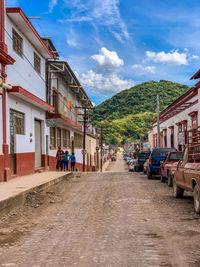 Road amidst buildings in city against sky