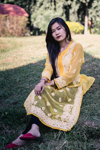 Beautiful young woman sitting on field