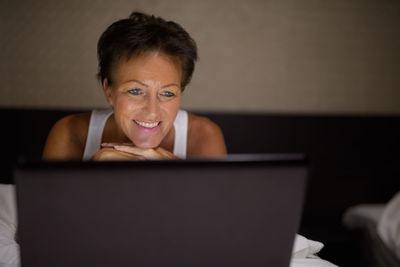 Portrait of smiling woman using laptop at home