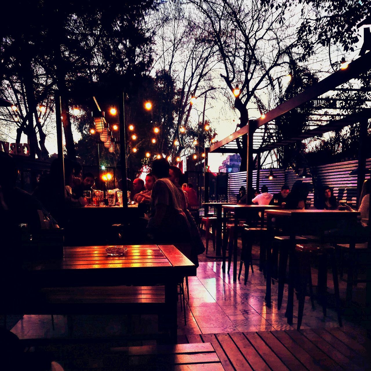 outdoor cafe, night, table, tree, real people, rear view, outdoors, illuminated, sitting, one person, sky, people