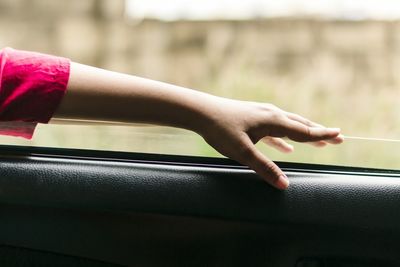 Cropped hand of woman on car window