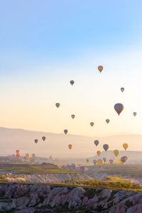 Hot air balloons flying over rocks against sky