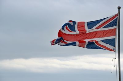 Low angle view of british flag waving against sky