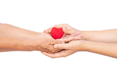 Close-up of hands holding heart shape over white background