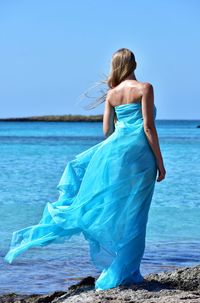 Rear view of woman at beach against sky