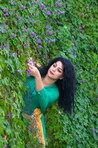 Beautiful young woman standing by flowering plants