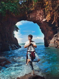 Man standing on rock by sea