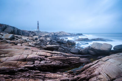 Scenic view of rocks by sea against sky