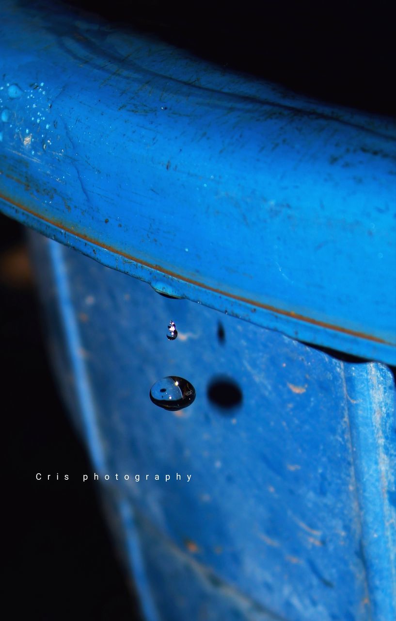 CLOSE-UP OF RAINDROPS ON BLUE GLASS