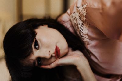 Close-up portrait of woman with hand on cheek at home
