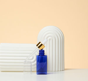 Blue glass bottle with pipette stands on a beige background. cosmetics spa branding. packaging