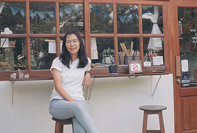 Portrait of smiling young woman sitting against window