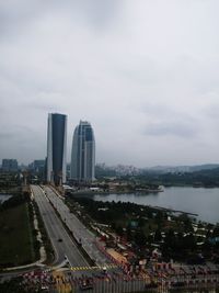 High angle view of city buildings against cloudy sky