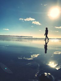 Silhouette man standing on beach against sky during sunset