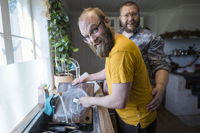 Smiling man washing dishes