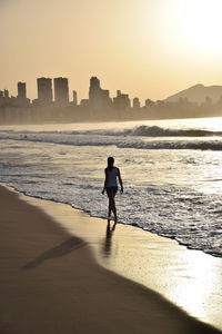 Full length of woman on beach against sky during sunset