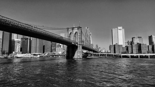 Low angle view of brooklyn bridge over east river against clear sky