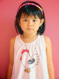 Portrait of girl standing against pink wall