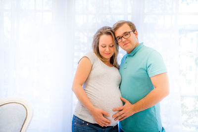 Portrait of couple standing against window