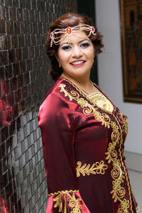 Portrait of woman in traditional clothing standing by wall