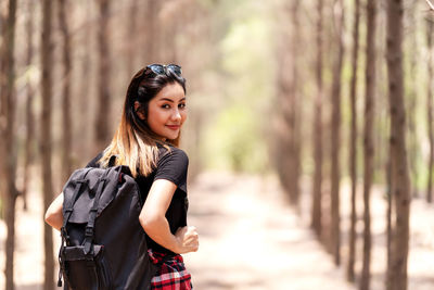 Portrait of woman standing against tree