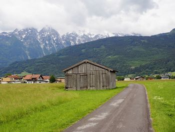 Road amidst houses and buildings against sky