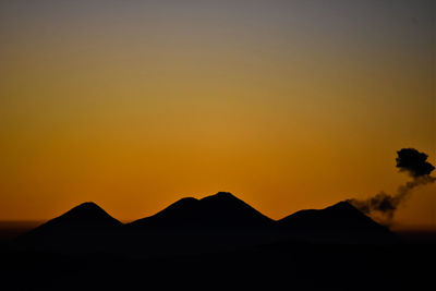 Scenic view of silhouette mountains against orange sky