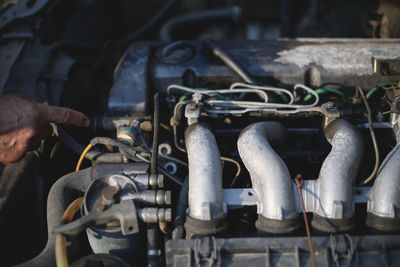 Cropped hand pointing at engine of car