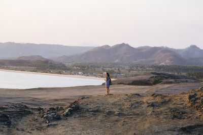 Young woman standing on rock at sunset