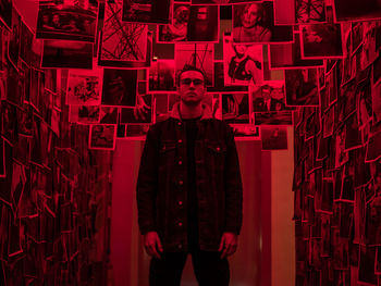 Portrait of man standing against illuminated red wall