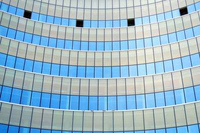 Low angle view of glass building against blue sky