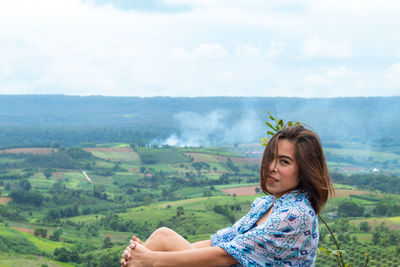 Portrait of woman sitting against landscape
