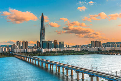 Scenic view of river and buildings against sky during sunset