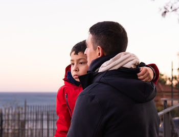 Side view of boy looking away while standing against sky