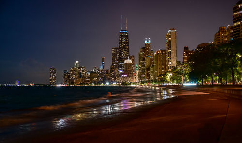 Illuminated modern buildings against sky at night