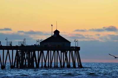 Silhouette pier over sea against sky during sunset