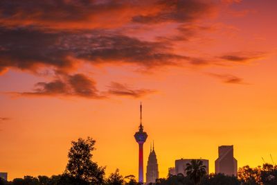 Silhouette buildings against cloudy sky during sunset