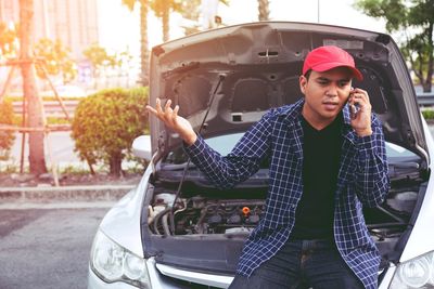 Man talking on phone while standing by broken car